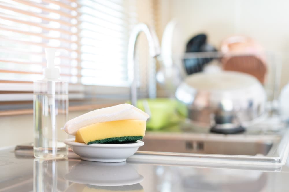 What should I avoid when cleaning my dish sponge